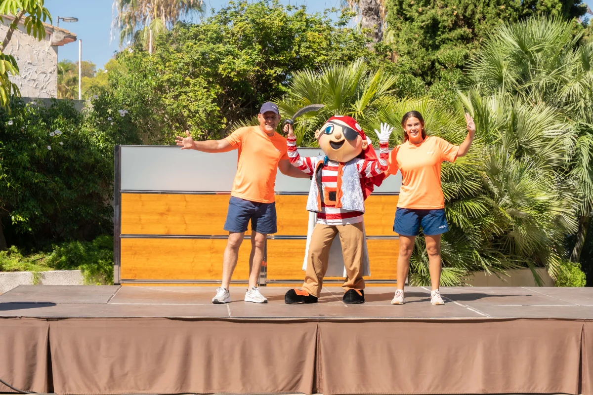 Persona disfrazada de pirata posa entre dos personas en un escenario.