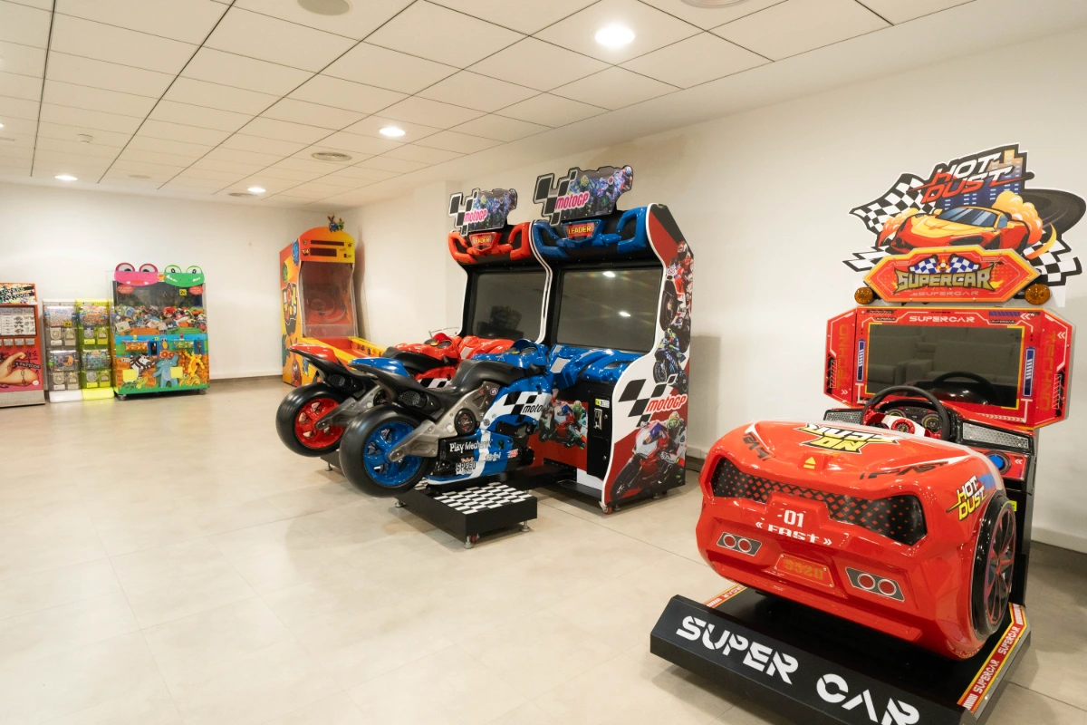 Sala de juegos arcade con motos y autos de carrera.