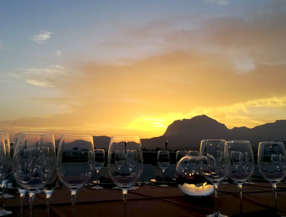 Copas de vino sobre una mesa al atardecer con monta&ntilde;as de fondo.