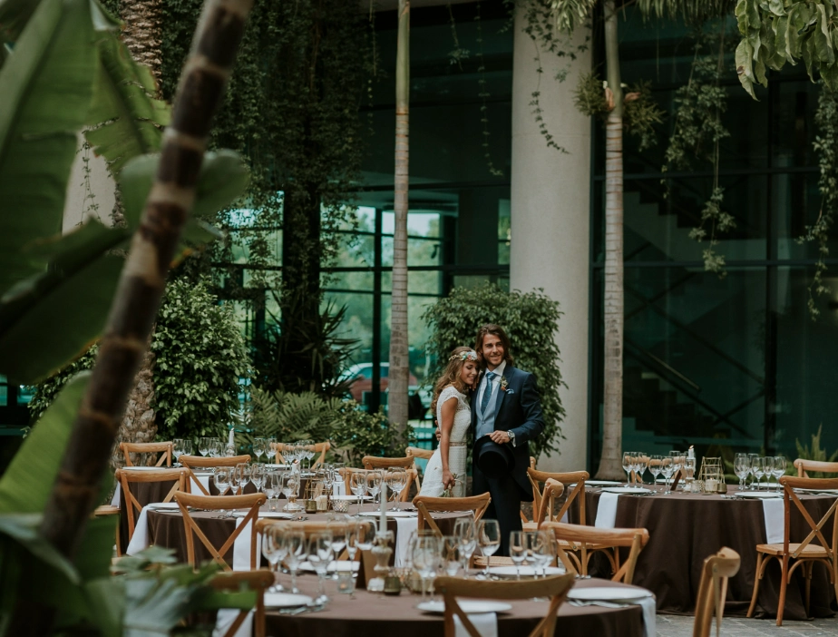 Pareja posando en una recepci&oacute;n elegante al aire libre con mesas decoradas.