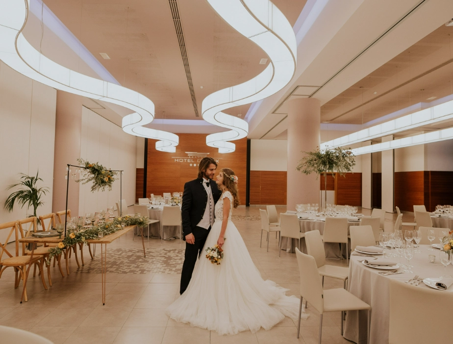 Pareja de novios en sal&oacute;n de bodas elegante con decoraci&oacute;n moderna.
