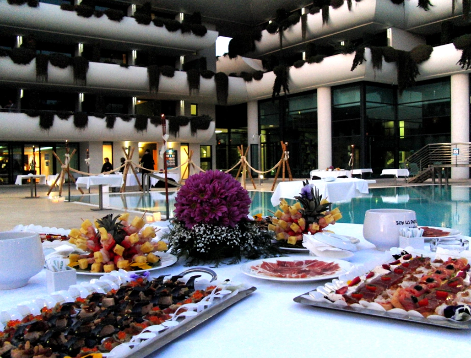 Buffet elegante junto a una piscina en un evento al aire libre por la tarde.