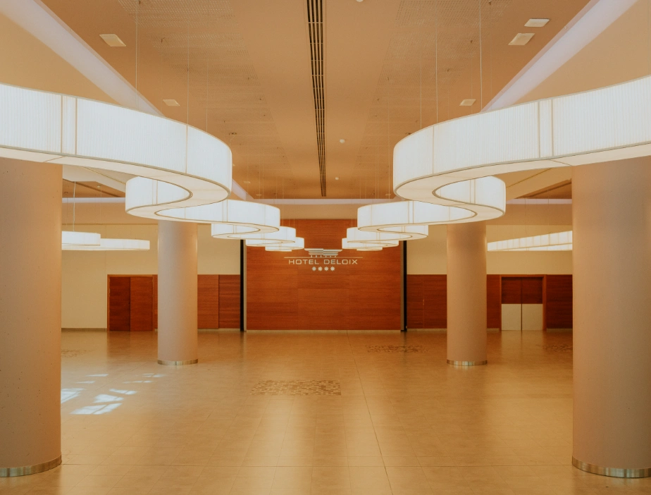 Lobby moderno con grandes l&aacute;mparas curvas y paredes de madera.