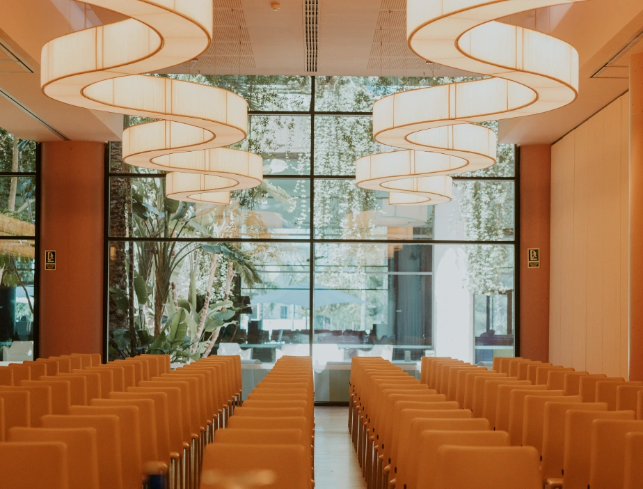 Sala de conferencias con l&aacute;mparas colgantes espirales y sillas ordenadas.