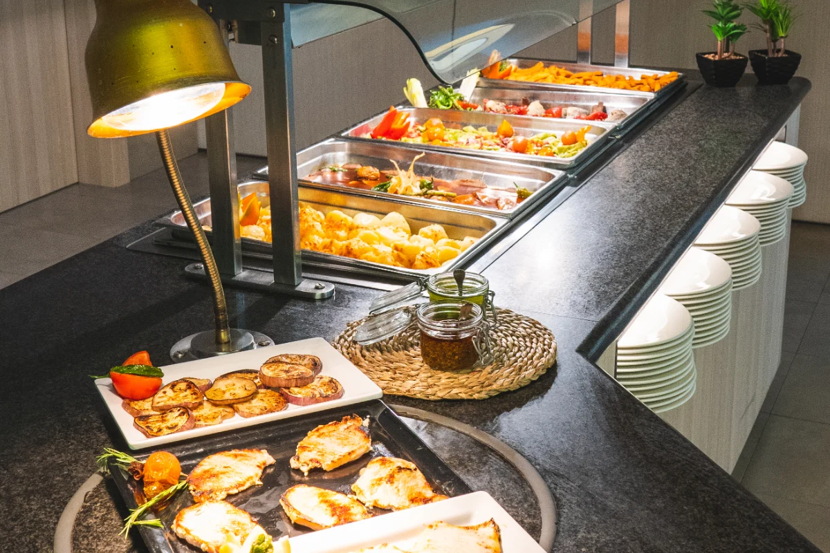 Buffet con platos variados, l&aacute;mpara y tarro de especias sobre la mesa.