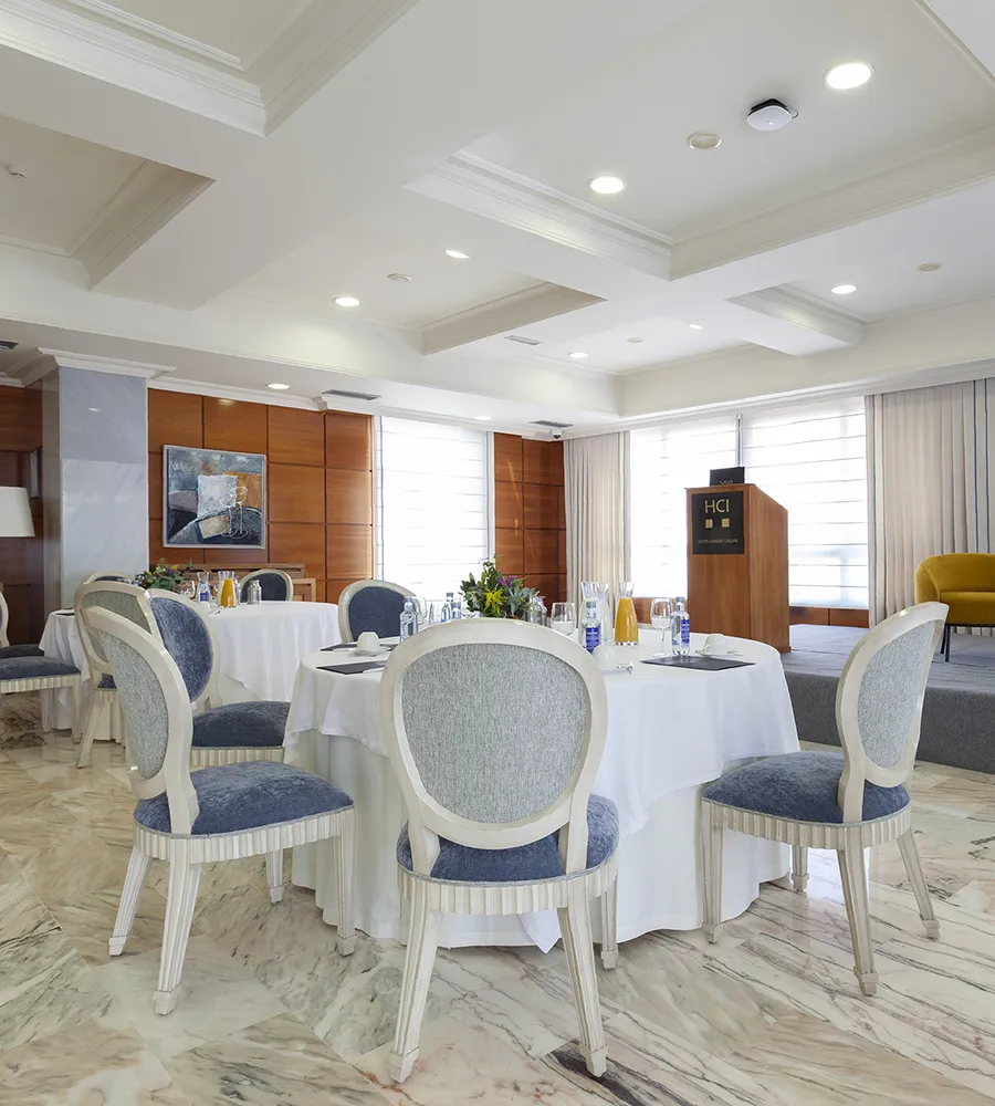 Sala de conferencias elegante con mesas redondas preparadas para un evento.