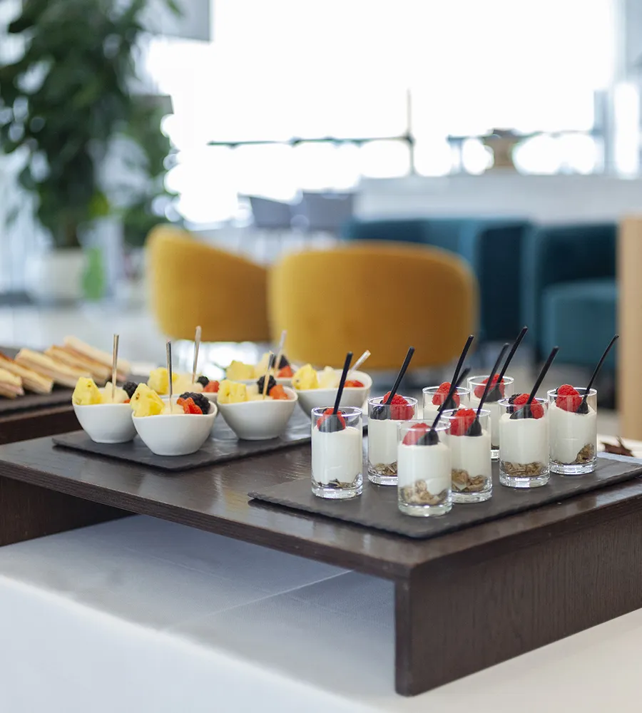 Postres y frutas servidos en un buffet elegante sobre mesa blanca.