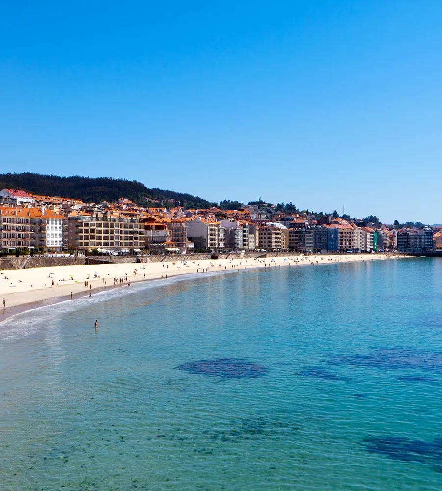 Playa con edificios, cielo despejado y agua cristalina.