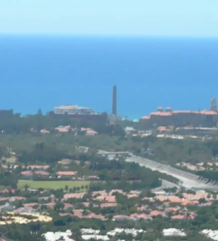 Vista a&eacute;rea de una ciudad costera con el mar azul al fondo.