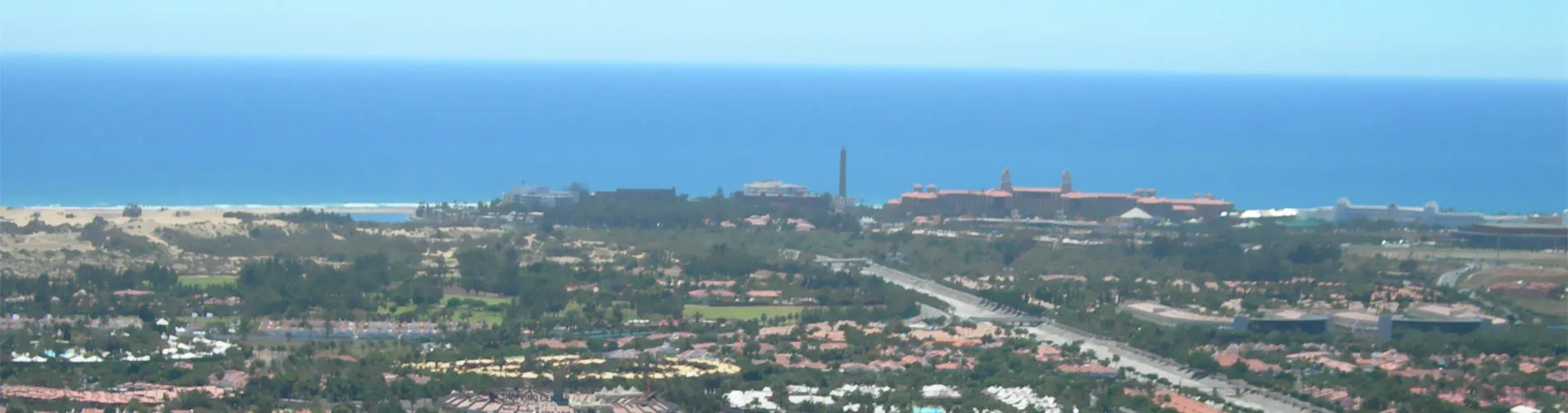 Vista panor&aacute;mica de una ciudad costera con el mar en el horizonte.