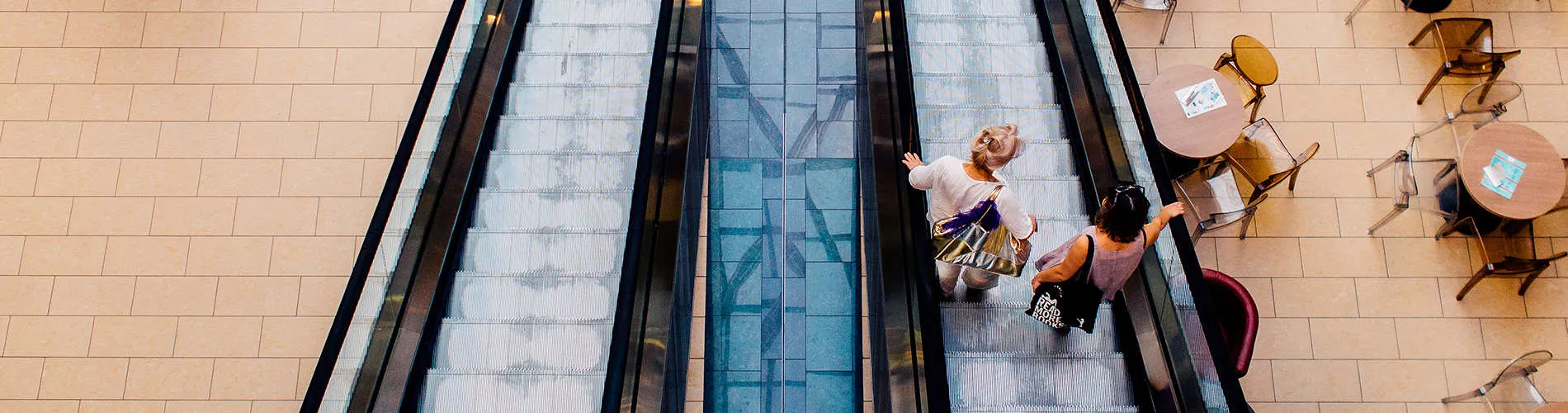 Personas bajando por una escalera mec&aacute;nica en un centro comercial.