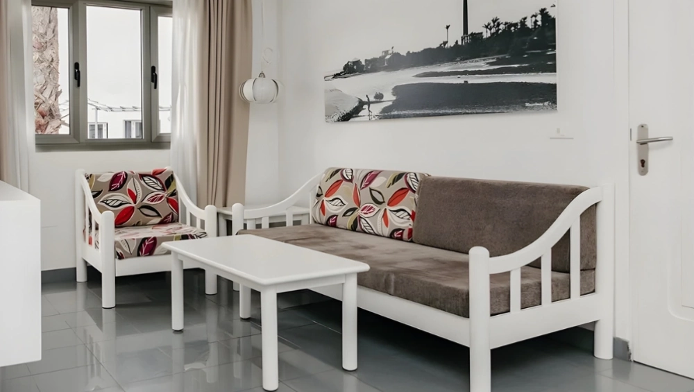 Sala moderna con sof&aacute; y silla estampados, mesa blanca y foto en blanco y negro.