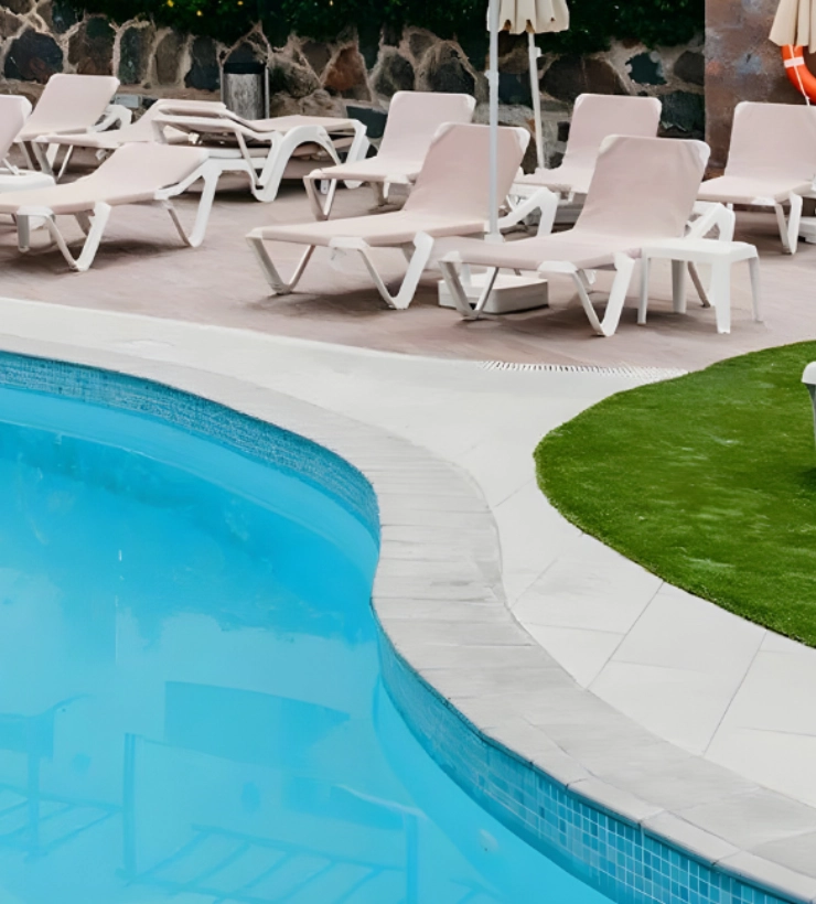Piscina con tumbonas y sombrillas a su alrededor.
