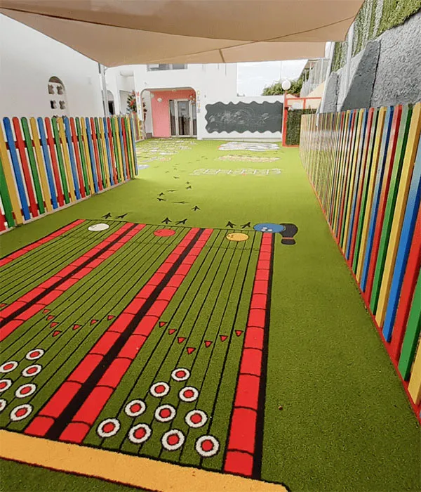 Patio de juegos con c&eacute;sped artificial y cercas de colores.