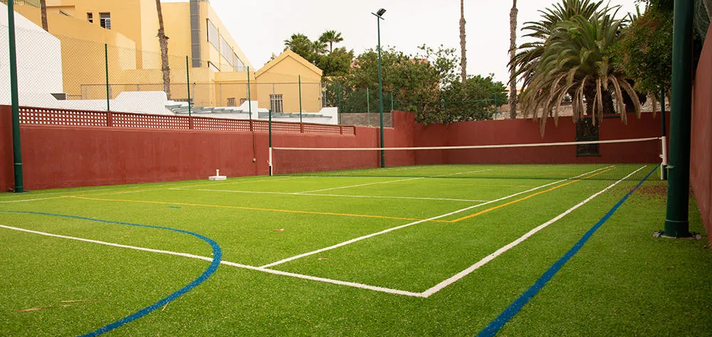 Cancha deportiva al aire libre con c&eacute;sped artificial y red.