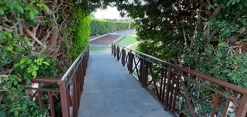 Sendero entre arbustos que lleva a un jard&iacute;n.