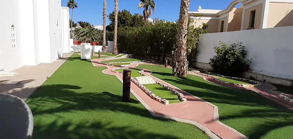 Minigolf al aire libre con c&eacute;sped artificial y palmeras alrededor.