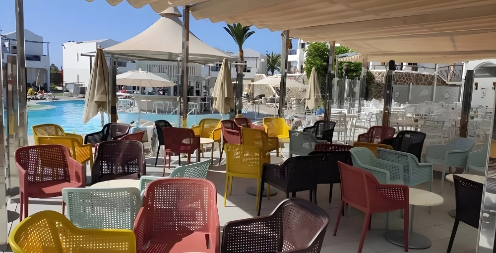 Sillas de colores en una terraza junto a una piscina en un d&iacute;a soleado.