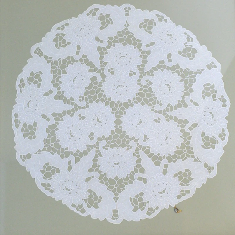 Intricate white lace doily with floral design on a flat surface.