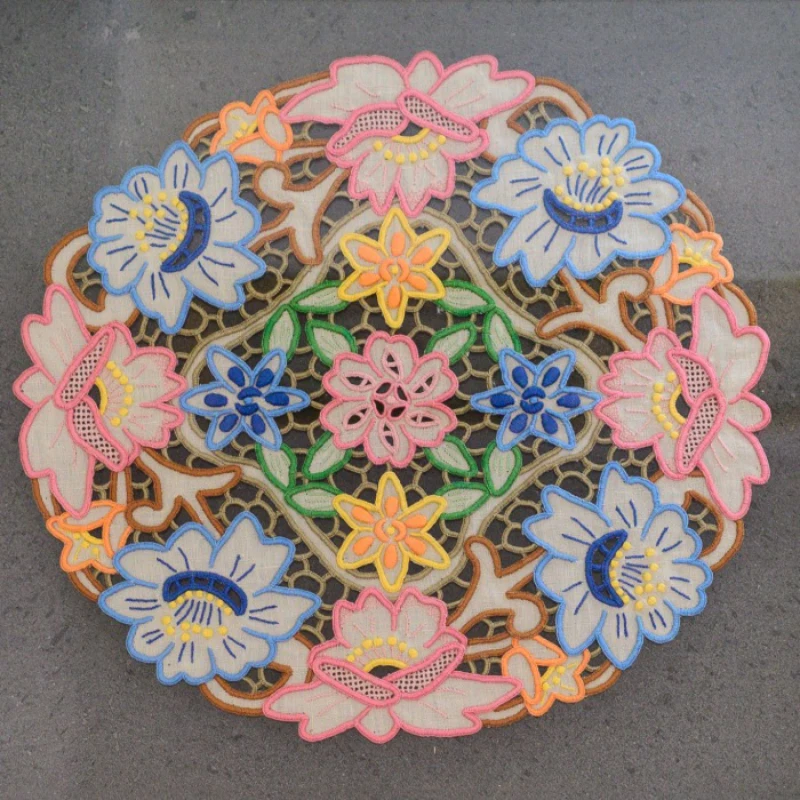 Ornate floral embroidery with colorful flowers on a dark surface.