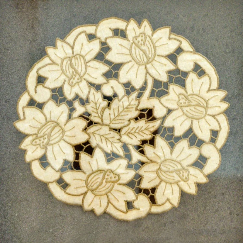 Intricate lace doily with floral design on a gray surface.