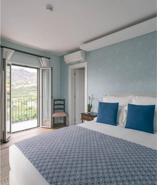 Stylish bedroom with blue accents and scenic balcony view.