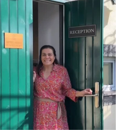 Person smiling at a green reception door entrance.