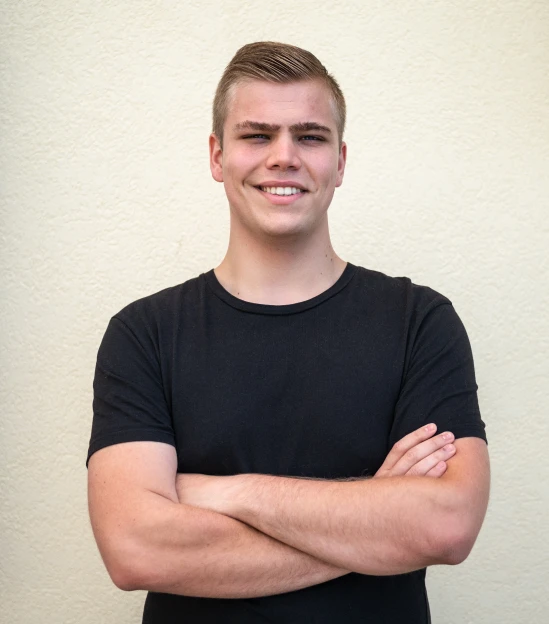 A person in a black shirt smiling with arms crossed.