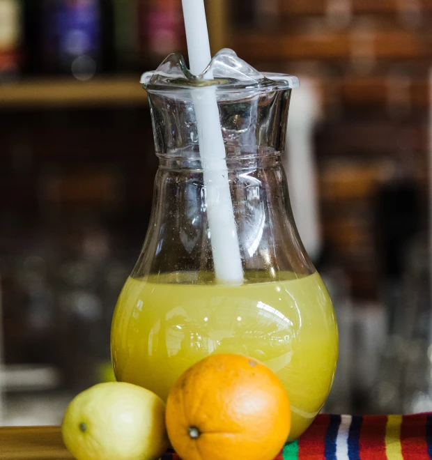 Pitcher of orange juice with lemon and orange in front.