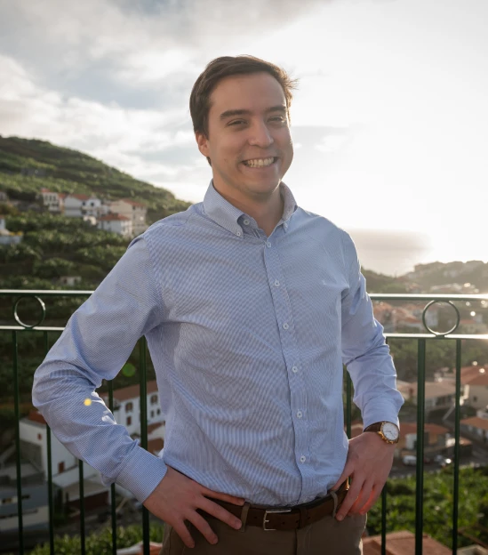 Smiling person standing with scenic hillside village view.