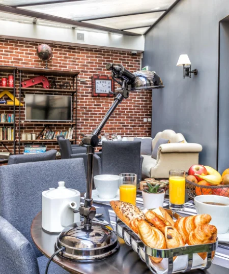 Petit-d&eacute;jeuner avec croissants, jus et caf&eacute; dans un salon moderne en brique.