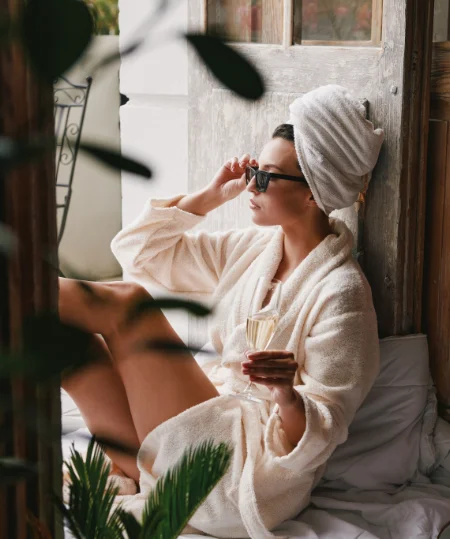 Personne en peignoir, tenant un verre et portant des lunettes de soleil.