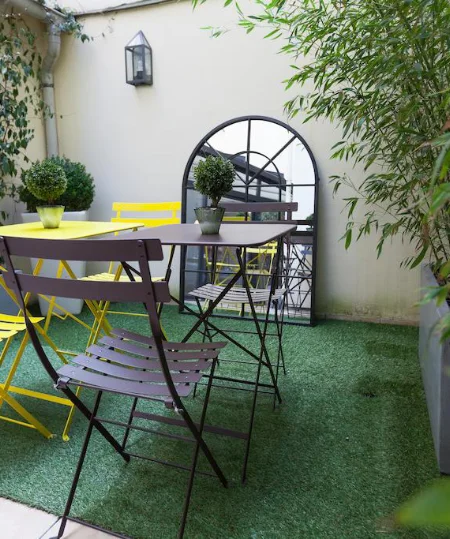 Petit jardin avec chaises color&eacute;es et miroir d&eacute;coratif.