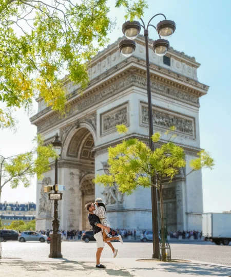 Couple joyeux devant l'Arc de Triomphe par une journ&eacute;e ensoleill&eacute;e.