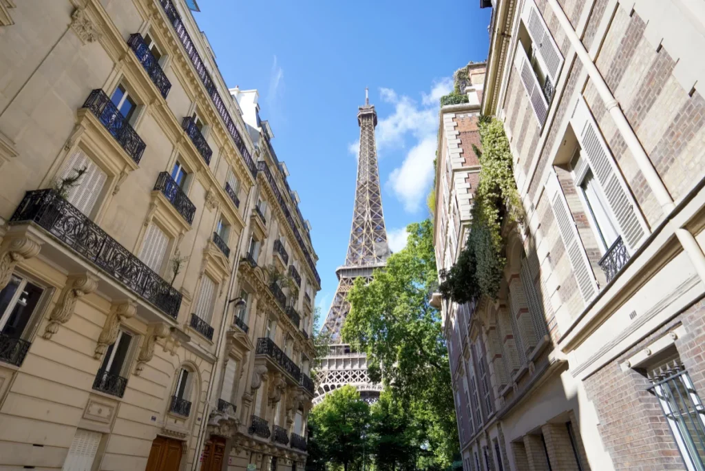 Rue parisienne avec vue sur la tour Eiffel entre des immeubles anciens.