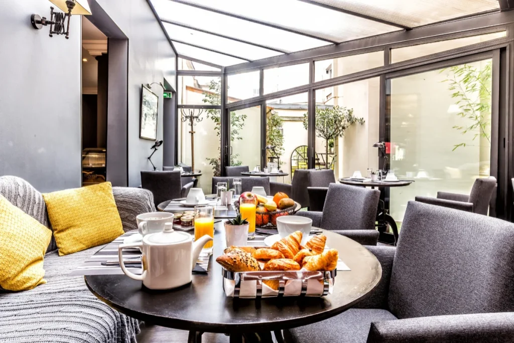 Salon lumineux avec tables dress&eacute;es pour le petit d&eacute;jeuner, vue sur patio.
