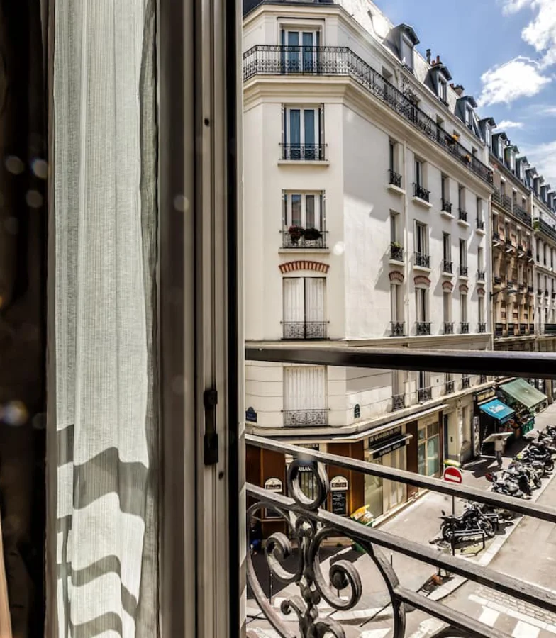 Vue d'une rue parisienne depuis une fen&ecirc;tre avec balcon en fer forg&eacute;.