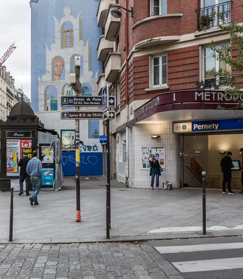 Entr&eacute;e de m&eacute;tro Pernety, une fresque murale et des passants.