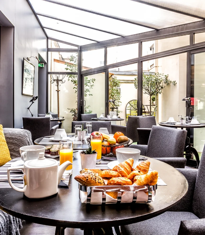 Petits-d&eacute;jeuners avec croissants et jus d'orange dans une salle vitr&eacute;e &eacute;l&eacute;gante.