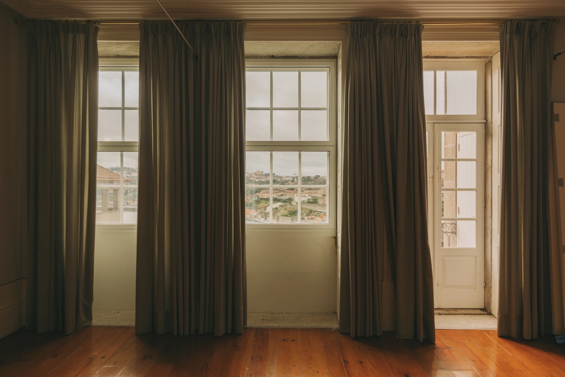Room with large windows and curtains open to a view outside.