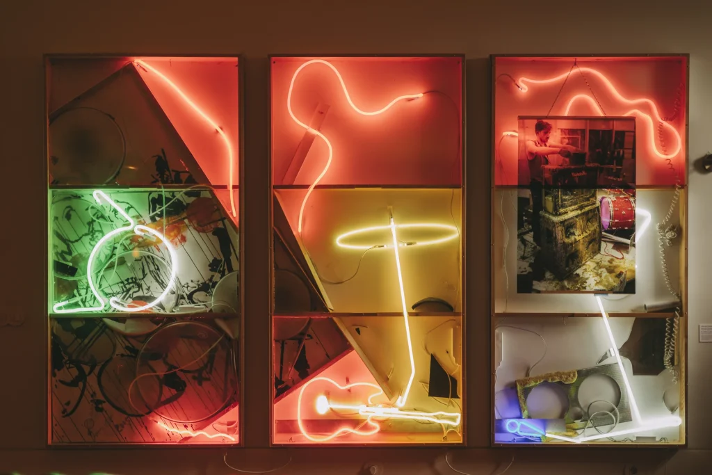 Neon art installation with abstract shapes and a photograph.