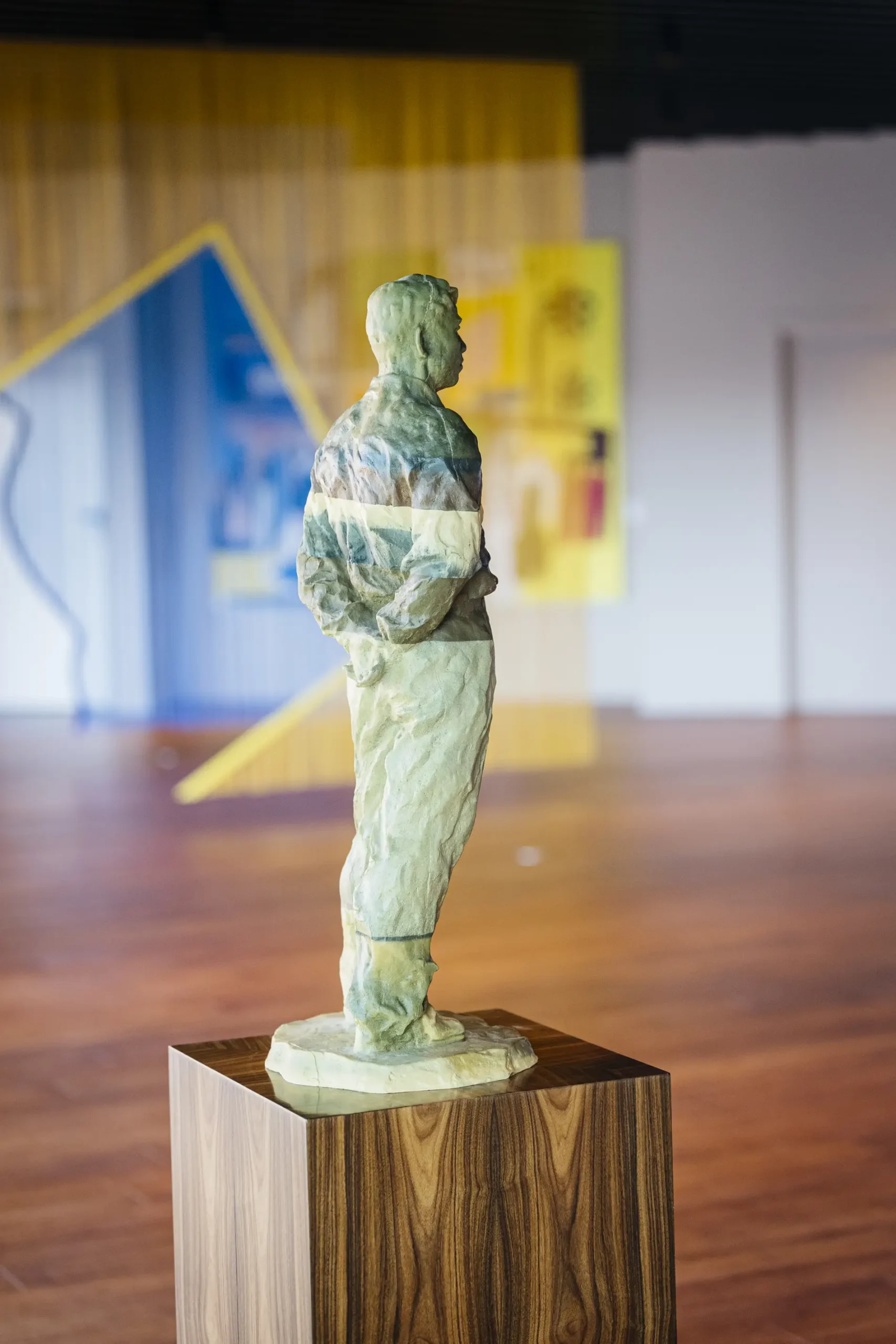 A marble statue of a man on a wooden pedestal indoors.