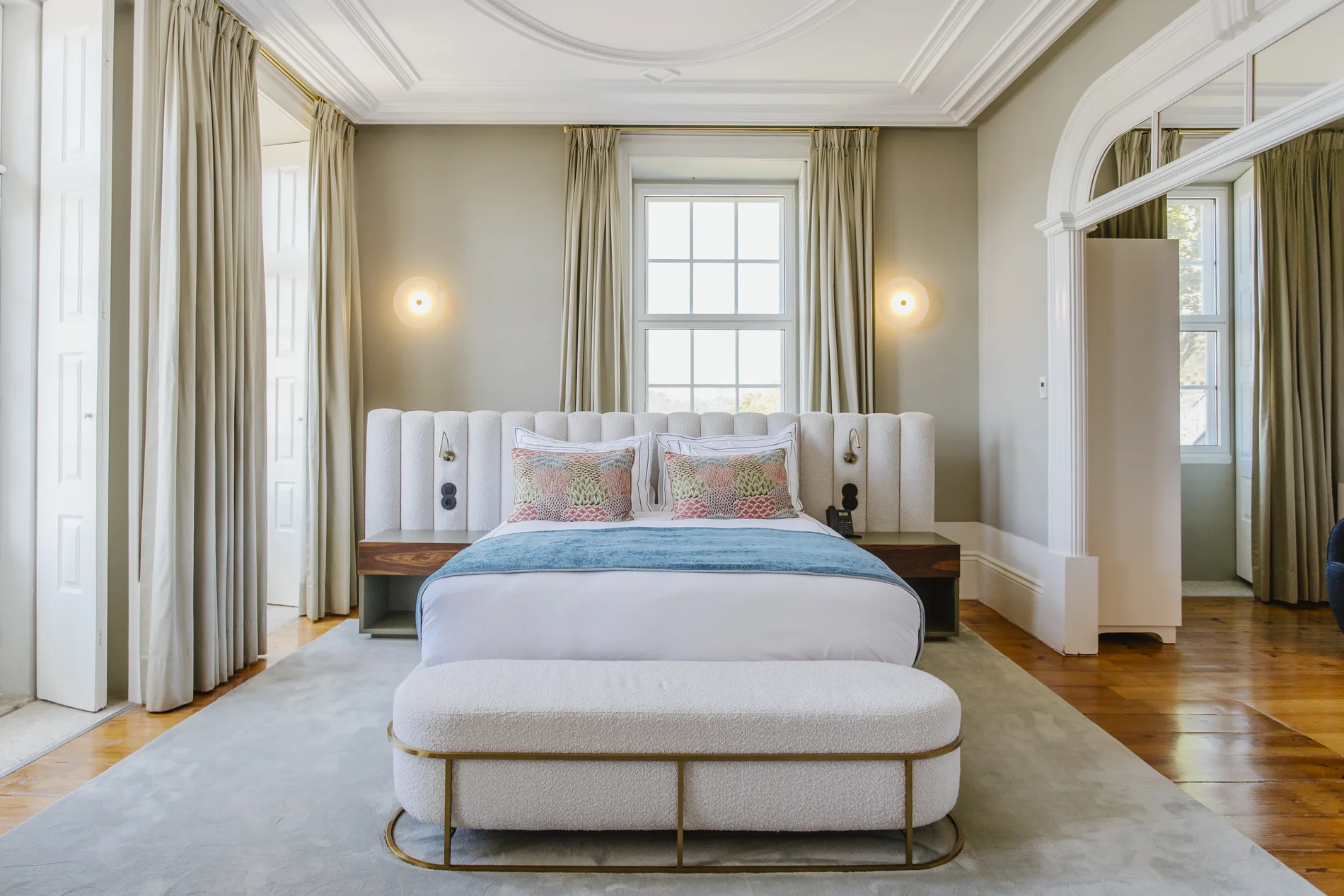 Elegant bedroom with large bed, patterned pillows, and soft lighting.