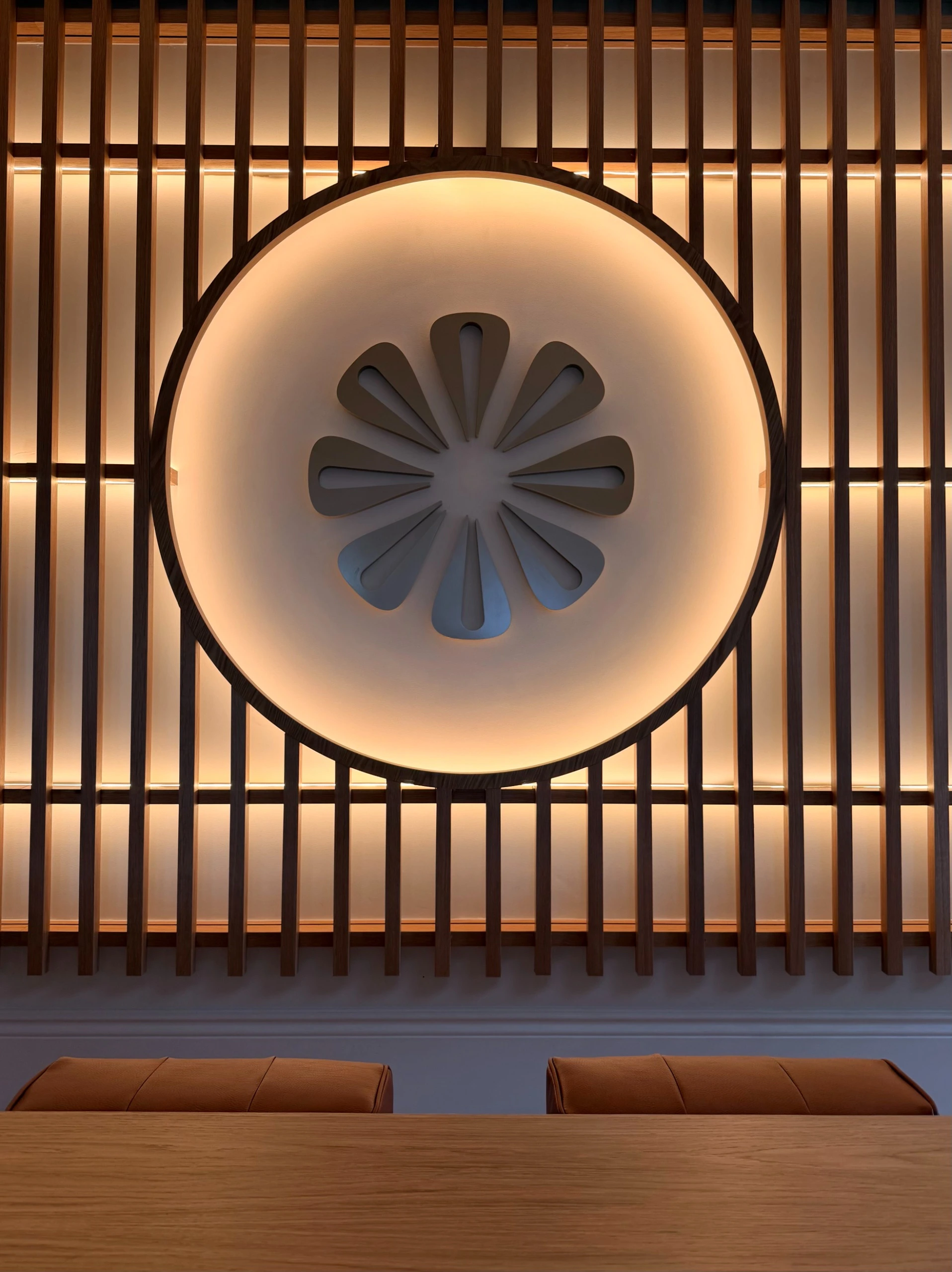 Letrero circular con un s&iacute;mbolo de flor de p&eacute;talos, iluminado tras barrotes de madera