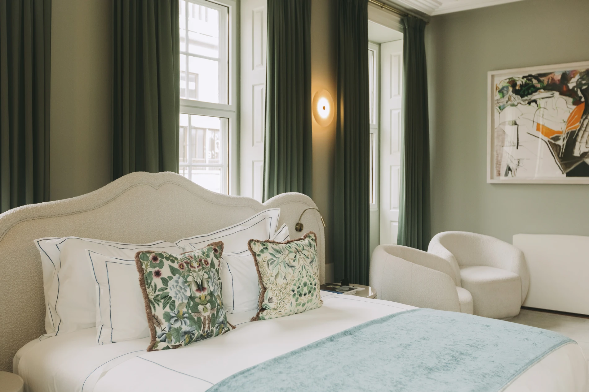 Elegant bedroom with floral pillows and green curtains.