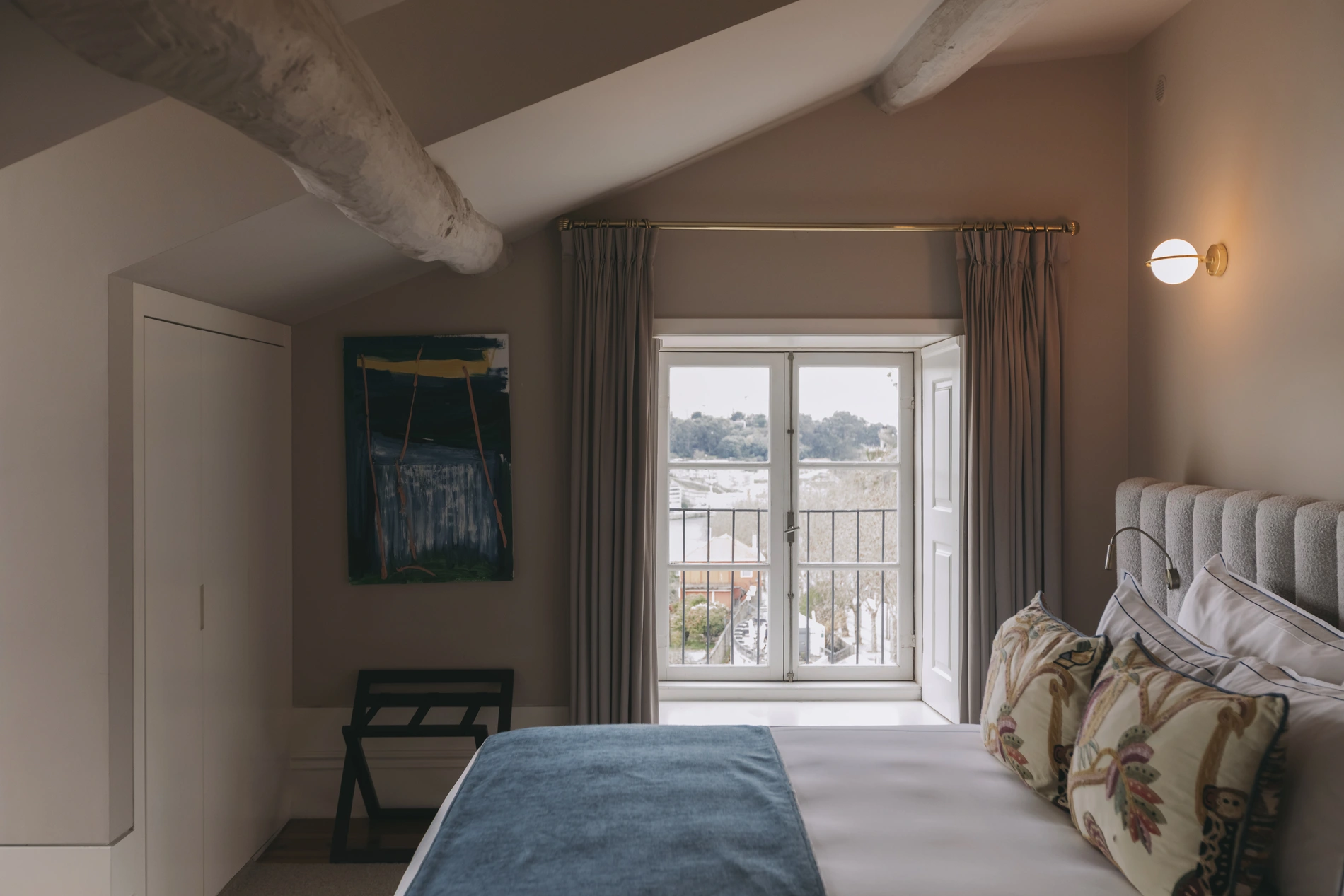 Cozy bedroom with bed, window view, and abstract wall art.