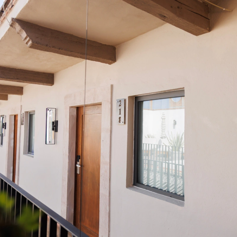 Puerta de madera con ventana, balc&oacute;n y techo de vigas oscuras. N&uacute;mero: 218.