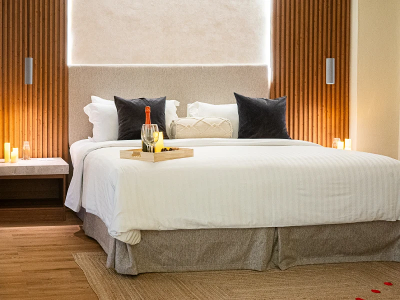 Cama con s&aacute;banas blancas y bandeja de desayuno en habitaci&oacute;n acogedora.