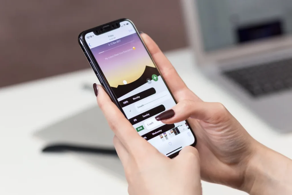 Persona usando un smartphone con una aplicaci&oacute;n abierta sobre atardecer.