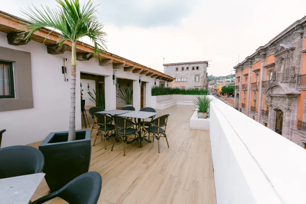 Terraza moderna con muebles, plantas y vista a edificios hist&oacute;ricos.